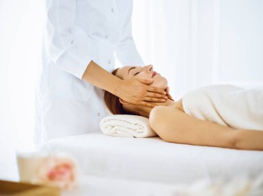 Kaplıca merkezinde gözleri kapalı yüz masajından hoşlanan güzel bir kadın.