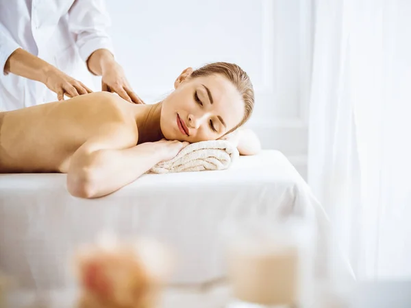 Piękna kobieta korzystająca z masażu pleców z zamkniętymi oczami. Koncepcja leczenia spa. — Zdjęcie stockowe