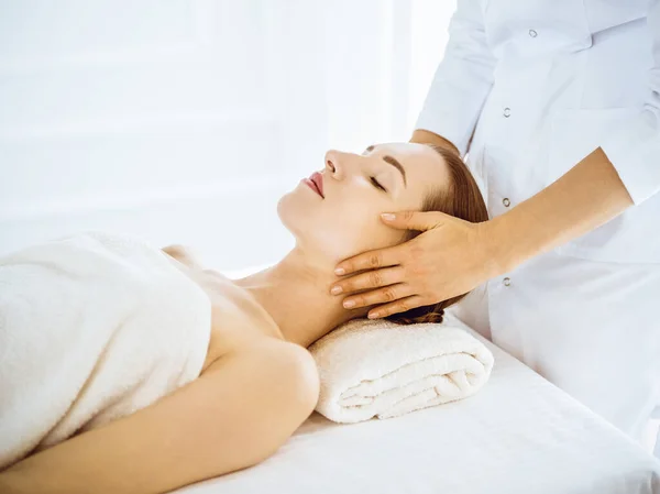 Piękna kobieta korzystających masaż twarzy z zamkniętymi oczami w centrum spa — Zdjęcie stockowe