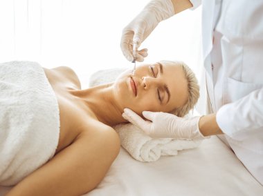 Güzellik uzmanı elleri şırıngayla kadın yüzüne güzellik prosedürü uyguluyor. Kozmetik tıp ve cerrahi, güzellik enjeksiyonları konsepti