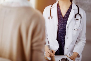 Doktor ve hasta güneşli klinikte otururken sağlık muayenesini tartışıyorlar. Hastanede mükemmel bir tıbbi hizmet.