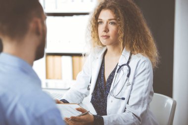 Kadın doktor ve erkek hasta klinikte otururken sağlık muayenesini tartışıyorlar. Tıp konsepti