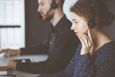 Modern ofiste otururken kulaklıkla konuşan kızıl sakallı bir iş adamı. Çağrı merkezinde çeşitli insanlar var. Tele pazarlama ve müşteri hizmetleri