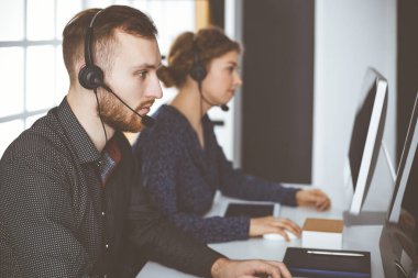 Modern ofiste otururken kulaklıkla konuşan kızıl sakallı bir iş adamı. Çağrı merkezinde çeşitli insanlar var. Tele pazarlama ve müşteri hizmetleri