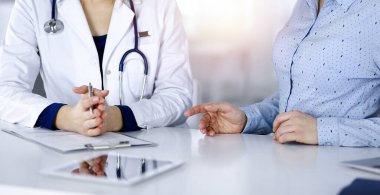 Bilinmeyen kadın. Doktor, bir klinikteki güneşli dolapta birlikte otururken hastasını dinliyor. Steteskoplu kadın doktor panoya yazı yazıyor, kapat. Mükemmel.