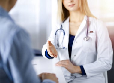 Bilinmeyen kadın-doktor bir klinikteki güneşli dolapta yan yana otururken hastasıyla konuşuyor. Steteskopu olan bir kadın doktor, yakın plan. Mükemmel bir tıbbi hizmet.