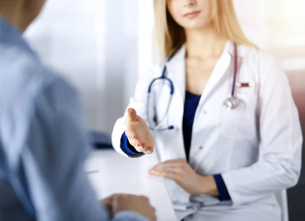 Mulher-médico desconhecido está conversando com seu paciente, enquanto eles estão sentados juntos no armário ensolarado em uma clínica. Médica com estetoscópio no trabalho, close-up. Serviço médico perfeito em um — Fotografia de Stock