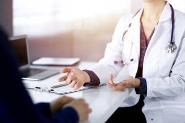 Bilinmeyen kadın-doktor, bir klinikteki güneşli dolapta birlikte otururken hastasına bazı tıbbi tavsiyeler yazıyor. Doktor bir pano kullanıyor, yakın plan.