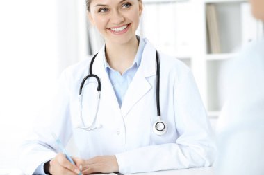 Dost canlısı gülümseyen doktor ve hasta masada oturuyor. Çok iyi haberler ve yüksek seviye tıbbi hizmet kavramı.