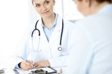 Dost canlısı gülümseyen doktor ve hasta masada oturuyor.