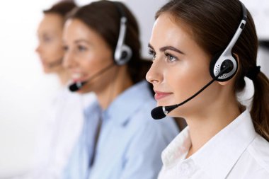 Merkezi ara. Bir grup operatör iş başında. Kulaklıklı güzel iş kadınına odaklan.