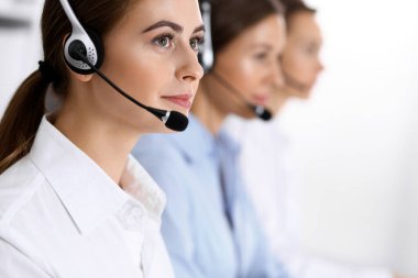 Merkezi ara. Bir grup operatör iş başında. Kulaklıklı güzel iş kadınına odaklan.