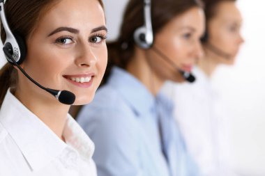 Merkezi ara. Bir grup operatör iş başında. Kulaklıklı güzel iş kadınına odaklan.