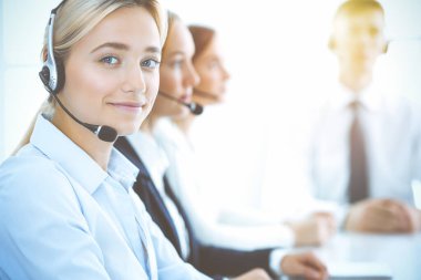 Kulaklıklı, güler yüzlü iş kadını müşterilere danışıyor. Sunny Office 'de çalışan çeşitli telefon operatörleri. Çağrı merkezi ve iş adamları kavramı.