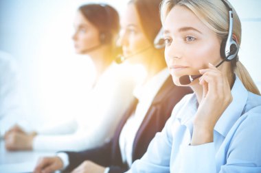 Kulaklıklı, güler yüzlü iş kadını müşterilere danışıyor. Sunny Office 'de çalışan çeşitli telefon operatörleri. Çağrı merkezi ve iş adamları kavramı.