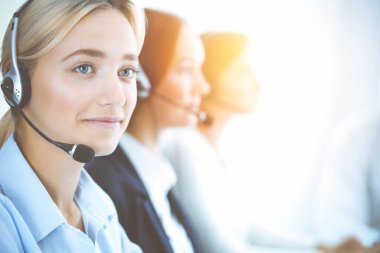 Kulaklıklı, güler yüzlü iş kadını müşterilere danışıyor. Sunny Office 'de çalışan çeşitli telefon operatörleri. Çağrı merkezi ve iş adamları kavramı.