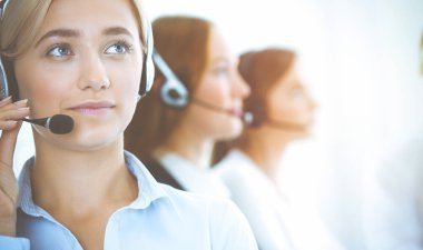 Kulaklıklı, güler yüzlü iş kadını müşterilere danışıyor. Sunny Office 'de çalışan çeşitli telefon operatörleri. Çağrı merkezi ve iş adamları kavramı.