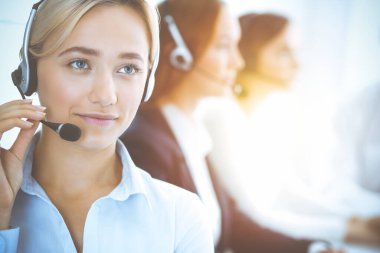 Kulaklıklı, güler yüzlü iş kadını müşterilere danışıyor. Sunny Office 'de çalışan çeşitli telefon operatörleri. Çağrı merkezi ve iş adamları kavramı.
