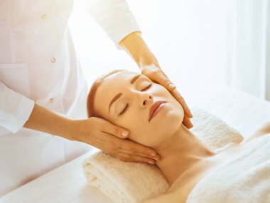 Güneşli spa merkezinde yüz masajından hoşlanan güzel bir kadın. Tıpta rahatlatıcı tedavi kavramı