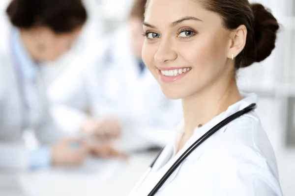 Glad leende kvinna-läkare sitter och tittar på kameran på möte med medicinsk personal. Medicinskt koncept — Stockfoto