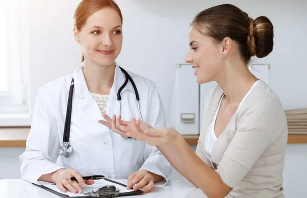 Médico y paciente sentado y discutiendo resultados de exámenes de salud en clínica soleada — Foto de Stock