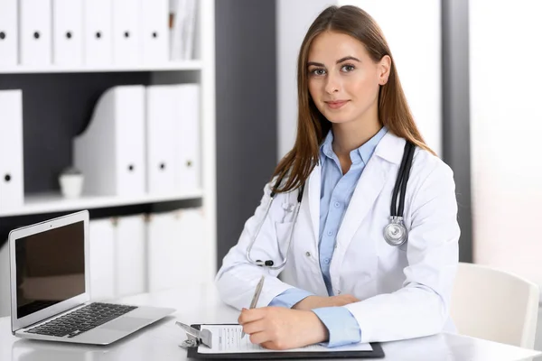 Mujer doctora llenando formulario médico mientras está sentada en el escritorio en la oficina del hospital. Médico trabajando. Concepto de medicina y salud — Foto de Stock