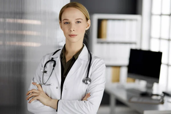 Amichevole dottoressa sorridente in piedi in clinica. Ritratto di donna medico amichevole. Servizio medico perfetto in ospedale. Concetto di medicina — Foto Stock