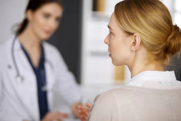 Femme souriante amicale médecin et patiente discutant de l'examen de santé en cours alors qu'elle était assise à la clinique. Médecine et concept de santé — Photo