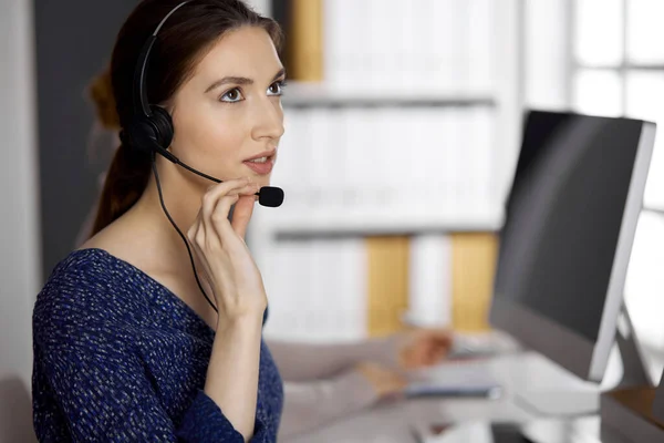 stock image Friendly asian or Latin american businesswoman talking by headset in office. Call center and diverse people group in business