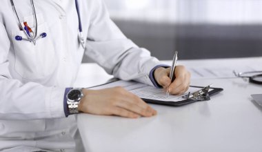 Bilinmeyen erkek doktor, klinikteki ilaç geçmişi kayıtlarıyla birlikte yakın planda oturuyor. İşteki genç doktor. Mükemmel sağlık hizmeti, tıp konsepti