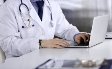 Bilinmeyen bir erkek doktor klinikte dizüstü bilgisayarla yakın planda çalışıyor. İşteki genç doktor. Mükemmel sağlık hizmeti, tıp konsepti