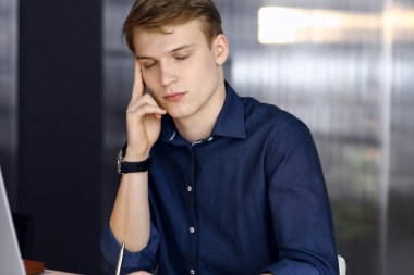 Genç sarışın iş adamı iş yerinde stres hissediyor. Girişim işi, başarı için çok çalışmak ve zamanın dışında çalışmak demektir.