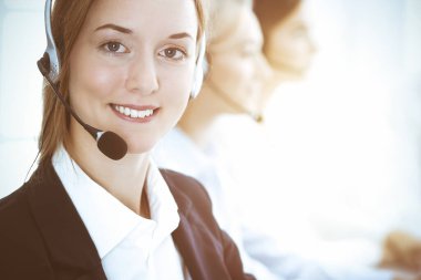 Çağrı merkezi ve iş adamları konsepti. Kulaklıklı güzel bir iş kadını müşterilerine danışıyor.