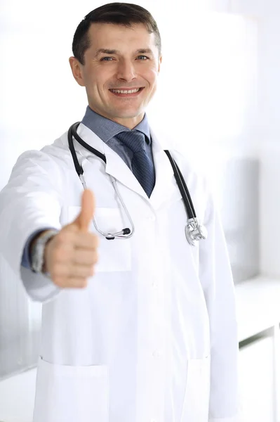 Доктор веселий посміхається на камеру, великі пальці вгору. Ідеальна медична служба в клініці. Щасливе майбутнє в медицині та медицині — стокове фото