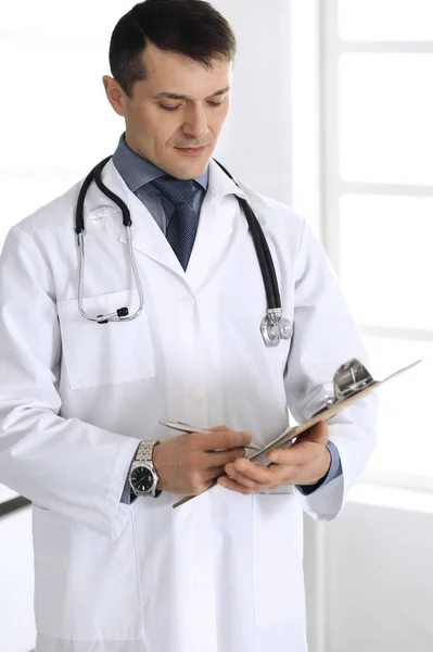 Doctor hombre usando portapapeles para llenar los registros del historial de medicamentos. Servicio médico perfecto en la clínica. Médico trabajando en el hospital. Medicina y conceptos sanitarios — Foto de Stock