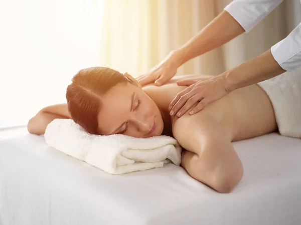 Ganska brunett kvinna njuter av proceduren med ryggmassage i solig spa salong. Skönhetsbegreppet — Stockfoto