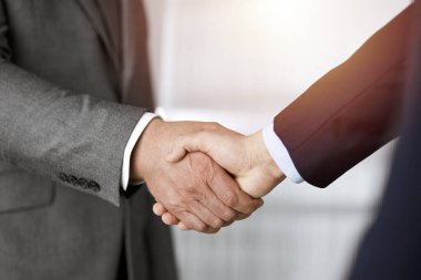 Güneşli ofiste el sıkışan iş adamları, yakın plan. El sıkışma ve pazarlama