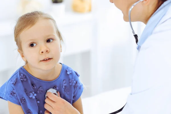 Docteur examinant une petite fille par stéthoscope. Heureux enfant patient souriant à l'inspection médicale habituelle. Médecine et concepts de santé — Photo