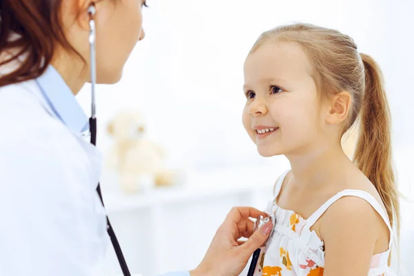 先生は聴診器で少女を調べる。通常の医療検査で幸せな笑顔の子供の患者.医学と医療の概念 — ストック写真
