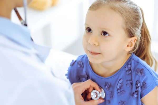 Doctor examinando a una niña por estetoscopio. Feliz niño sonriente paciente en la inspección médica habitual. Medicina y conceptos sanitarios —  Fotos de Stock