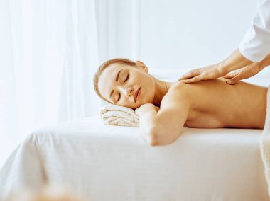 Güzel bir kadın kapalı gözlerle sırt masajından hoşlanıyor. Spa tedavisi kavramı