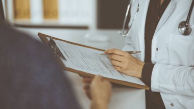 Doktor ve hasta klinikte otururken sağlık muayenesini tartışıyorlar. Hastanede mükemmel bir tıbbi hizmet.