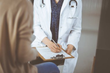 Doktor ve hasta klinikte otururken sağlık muayenesini tartışıyorlar. Hastanede mükemmel bir tıbbi hizmet.