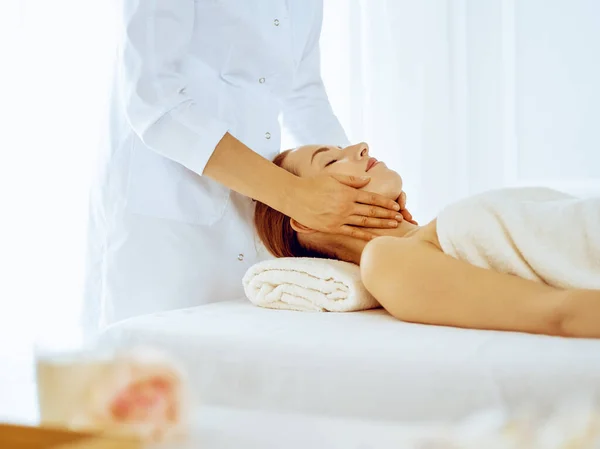 Hermosa mujer disfrutando de masaje facial con los ojos cerrados en el centro de spa. Relajarse concepto de tratamiento en la medicina — Foto de Stock