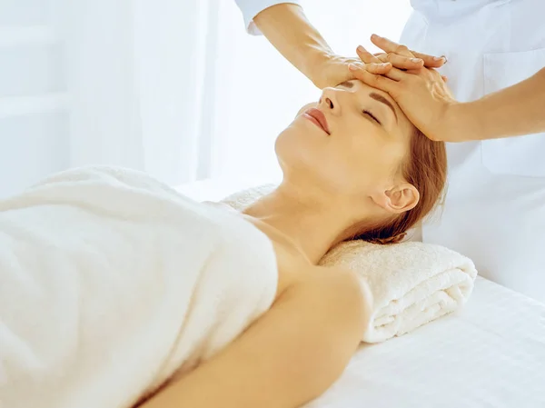 Piękna kobieta korzystająca z masażu twarzy z zamkniętymi oczami w centrum spa. Rozluźnij koncepcję leczenia w medycynie — Zdjęcie stockowe