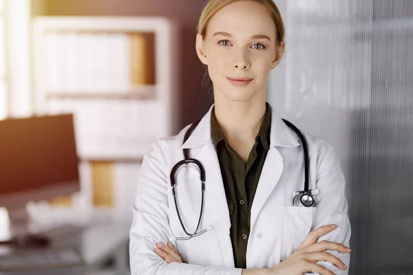 Allegro sorridente medico donna in piedi in clinica soleggiata. Ritratto di donna medico amichevole. Servizio medico perfetto in ospedale. Concetto di medicina — Foto Stock