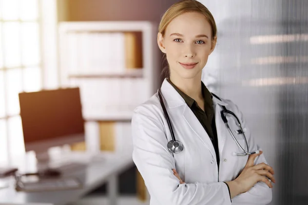 Allegro sorridente medico donna in piedi in clinica soleggiata. Ritratto di donna medico amichevole. Servizio medico perfetto in ospedale. Concetto di medicina — Foto Stock