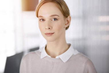 Dost canlısı, sıradan giyinmiş iş kadını dik duruyor. Güneşli bir iş vesikalığı ya da ofis portresi kavramı