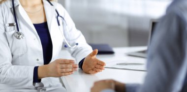 Bilinmeyen kadın-doktor bir klinikteki dolapta yan yana otururken hastasıyla konuşuyor. Steteskopu olan bir kadın doktor, yakın plan. Hastanede mükemmel bir tıbbi hizmet.