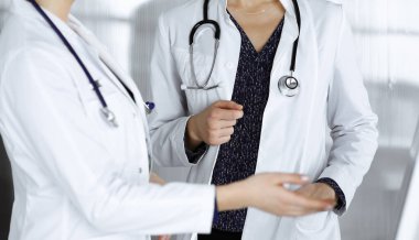 İki kadın hekim klinikteki masada dururken tıbbi terapiyi tartışıyorlar. Doktorlar işte bilgisayar kullanırlar. Tıpta takım çalışması